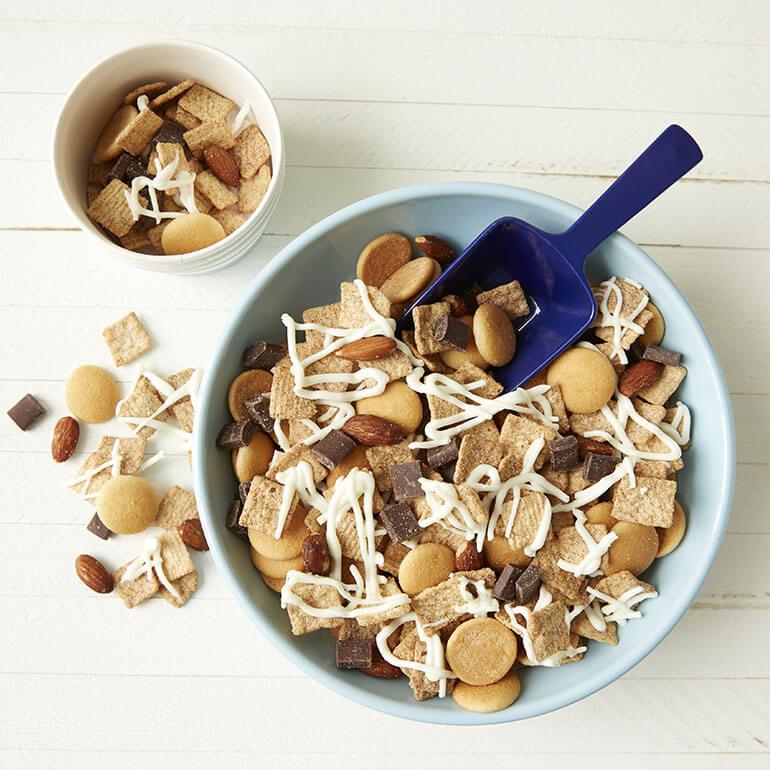 A bowl of Cinnamon Toast Crunch™ Churro Snack Mix on a white painted surface.