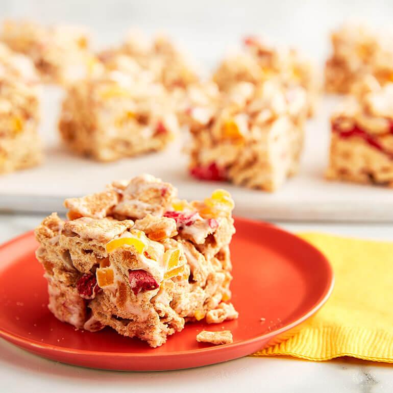 A No-Bake Fruity Cinnamon Toast Crunch™ Cereal Bar on a plate with the rest of the bars behind it.